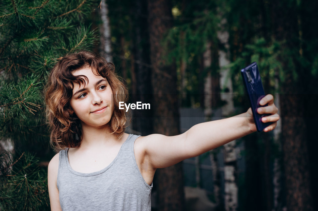 Beautiful teenager girl taking a selfie at the forest.