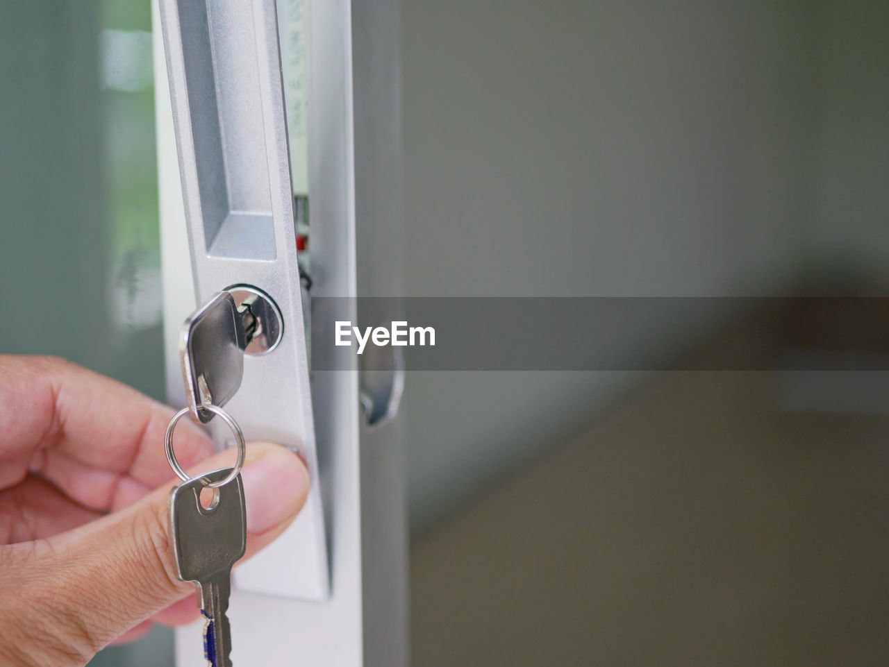 Cropped hands of person adjusting lock on glass door
