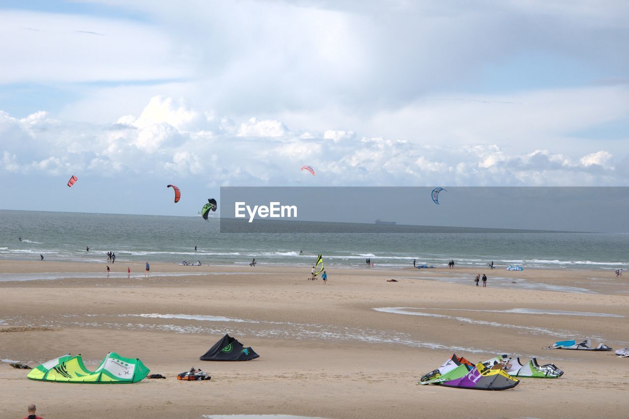 People kiteboarding on sea shore against sky