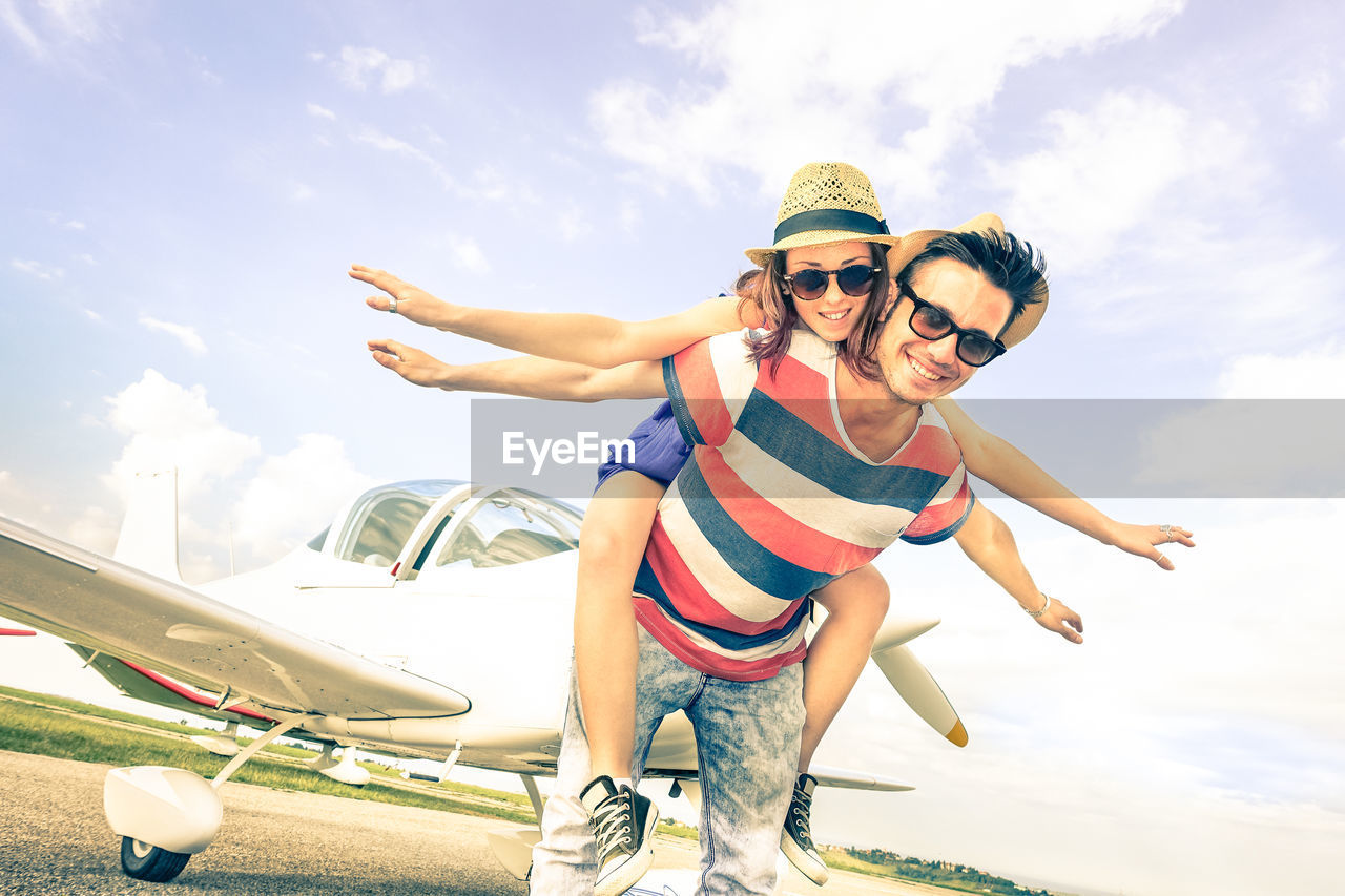 Portrait of smiling young friends against sky