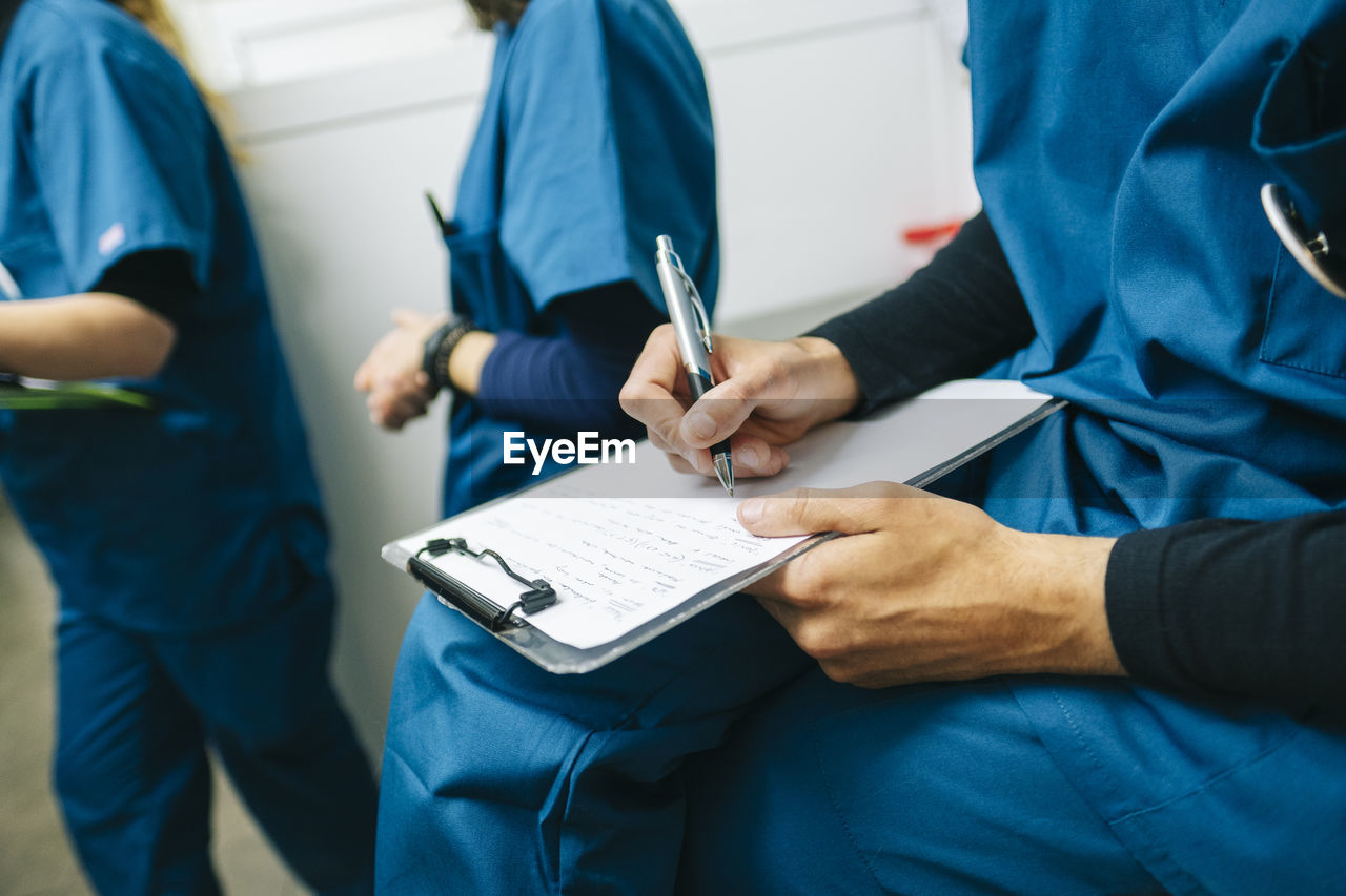 Male nurse writing medical report while sitting in veterinary clinic