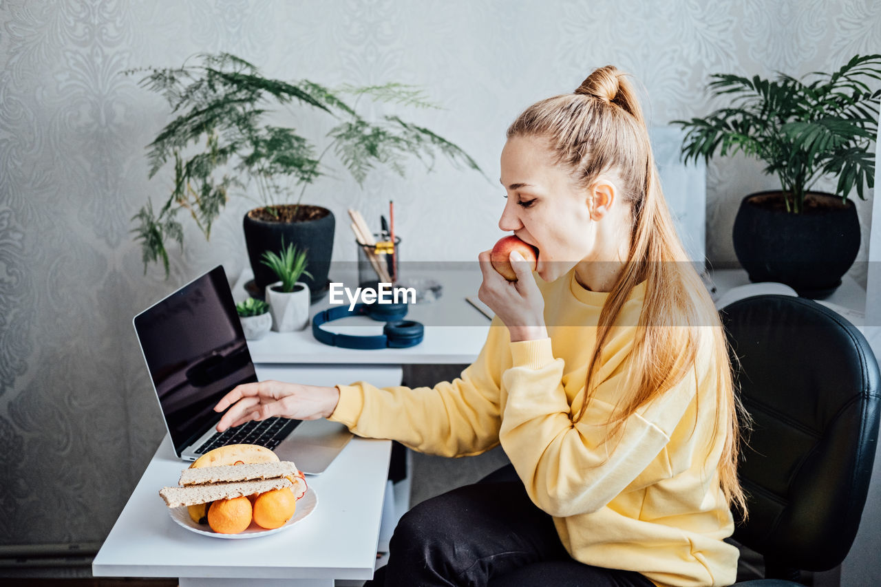 Freelancer young woman eating healthy food when working from home. woman eating healthy grain