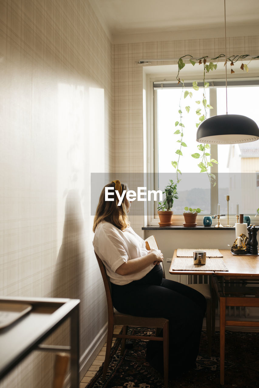 Pregnant woman sitting in kitchen