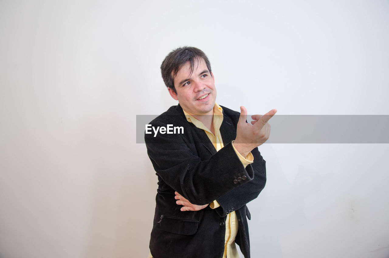 Businessman pointing while looking away against white background