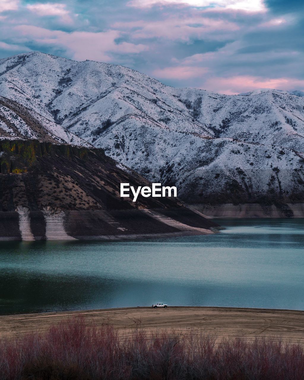 Scenic view of lake by snowcapped mountains against sky