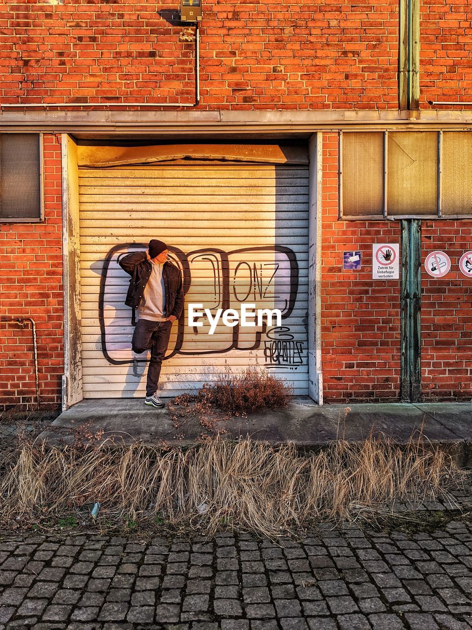 Full length of man standing on brick wall