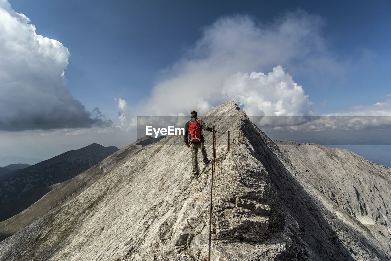 Rear view of man standing on mountain against sky