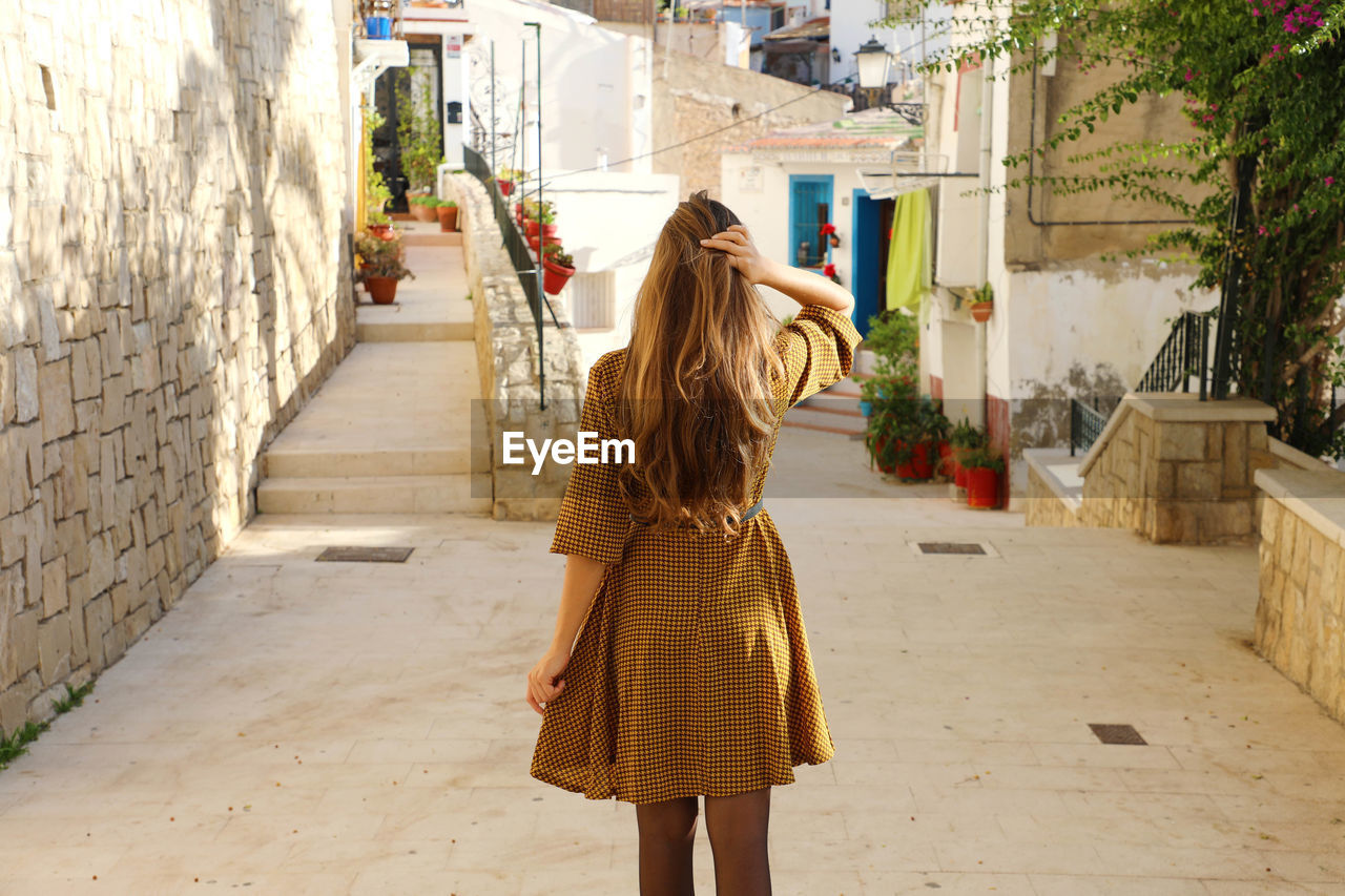 Rear view of woman standing on footpath in city