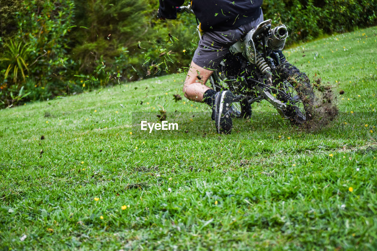Low section of man riding motorcycle on grassy field