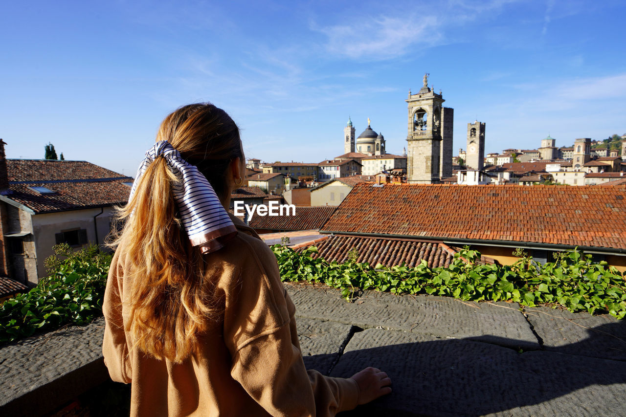 Rear view of girl looking the cityscape of bergamo, lombardy, italy