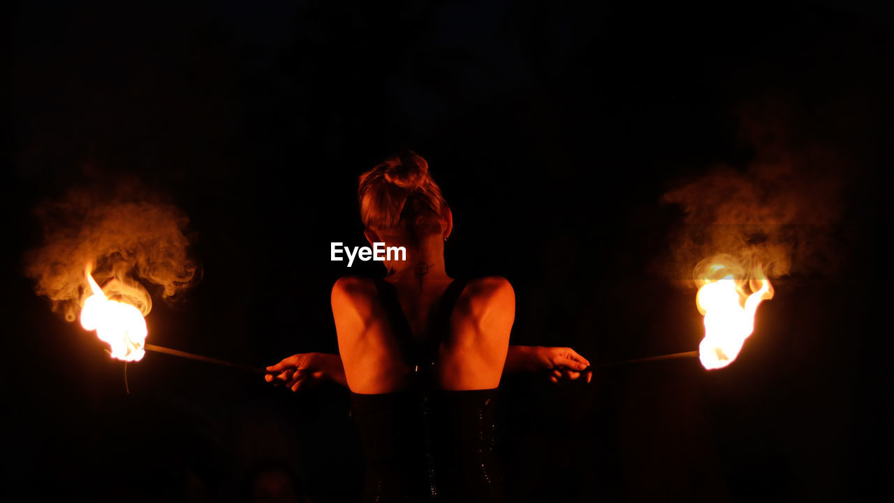 Rear view of woman doing fire stunt night