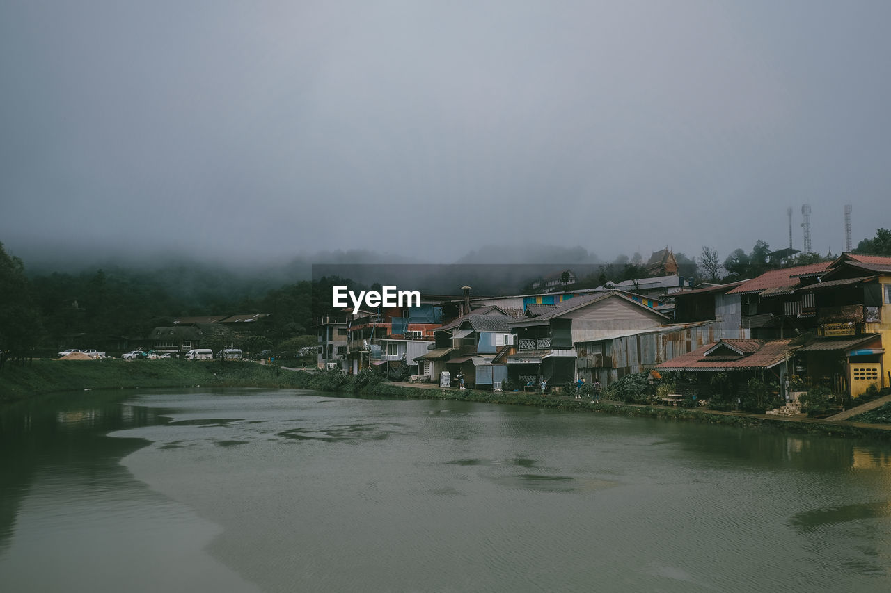 River amidst houses and buildings against sky