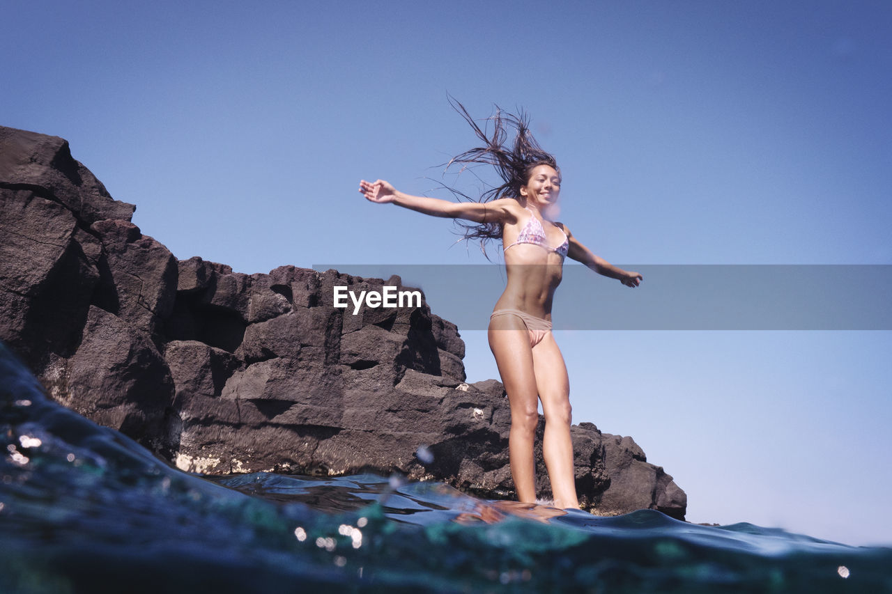Smiling woman with arms outstretched jumping into water
