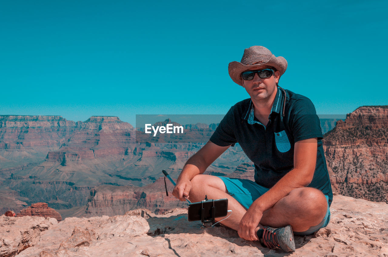 Man sitting against clear blue sky at grand canyon national park