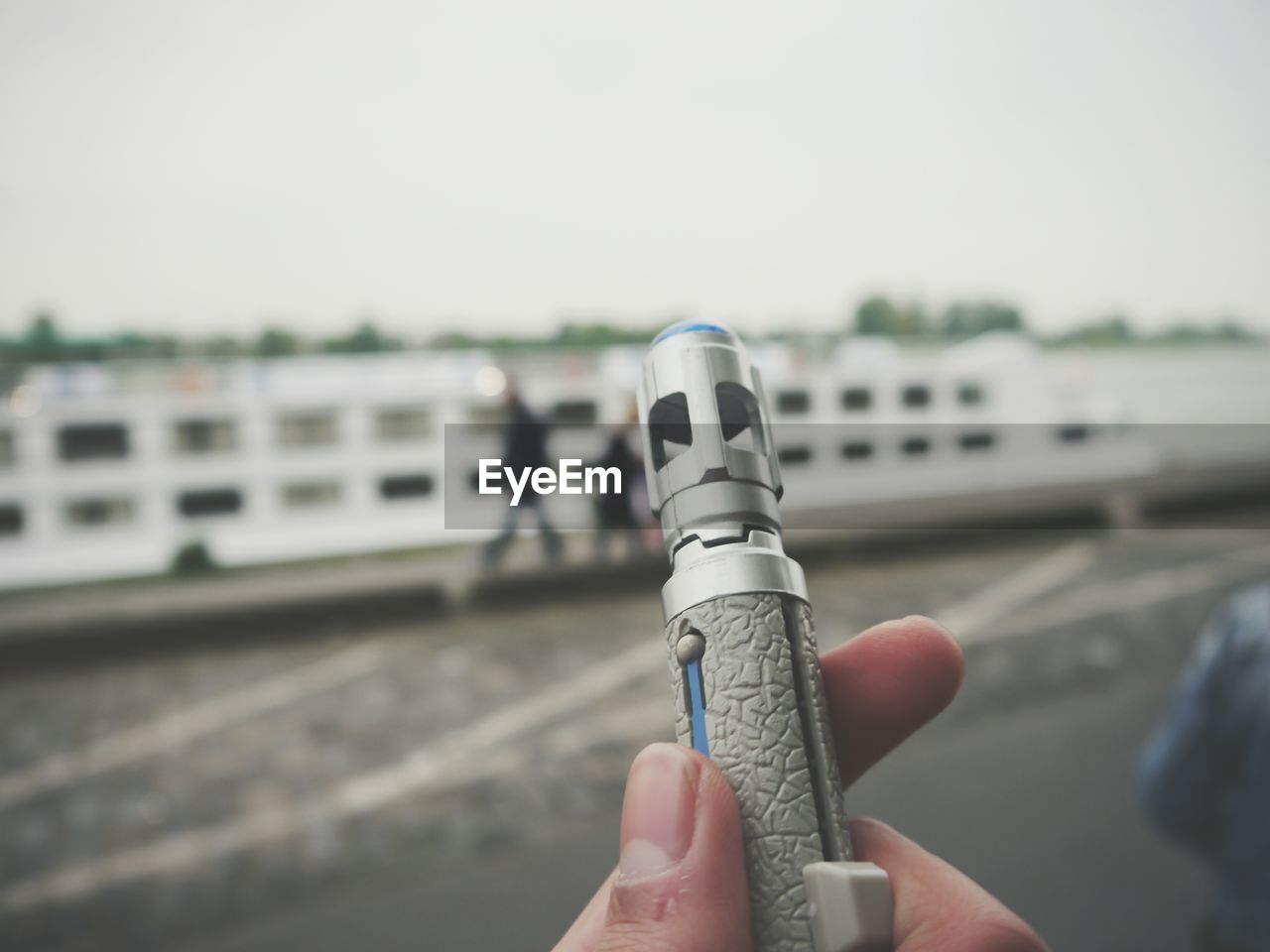 CLOSE-UP OF HAND HOLDING UMBRELLA AGAINST SKY