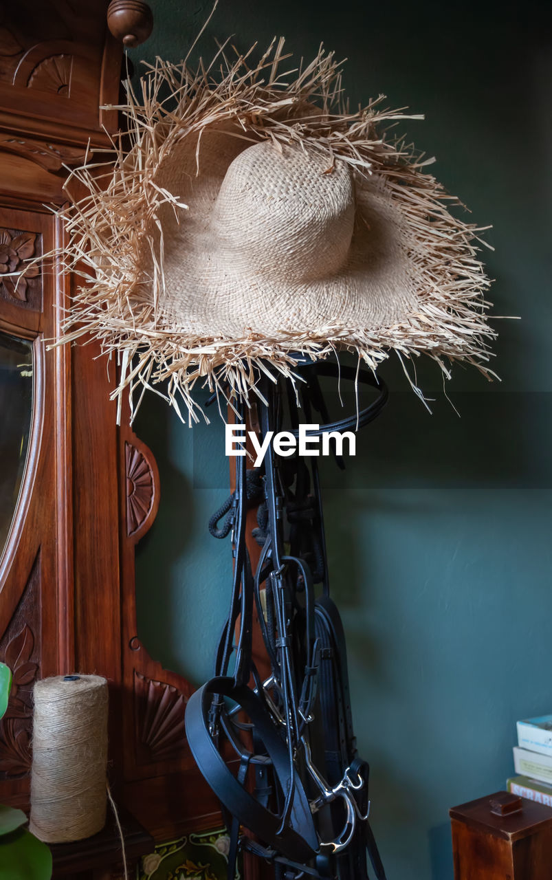 Close-up of straw hat hanging by wall at home