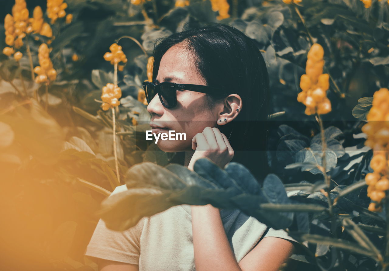 Close-up of young woman standing by plants