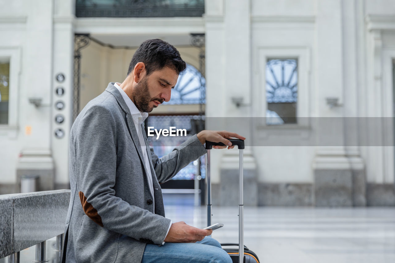 YOUNG MAN USING MOBILE PHONE IN OFFICE