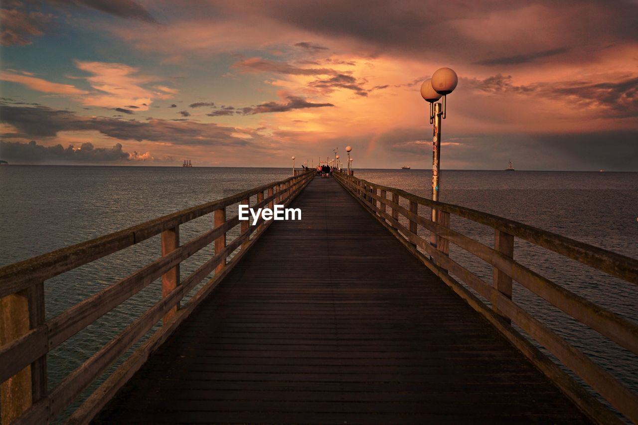 Pier over sea against sky during sunset