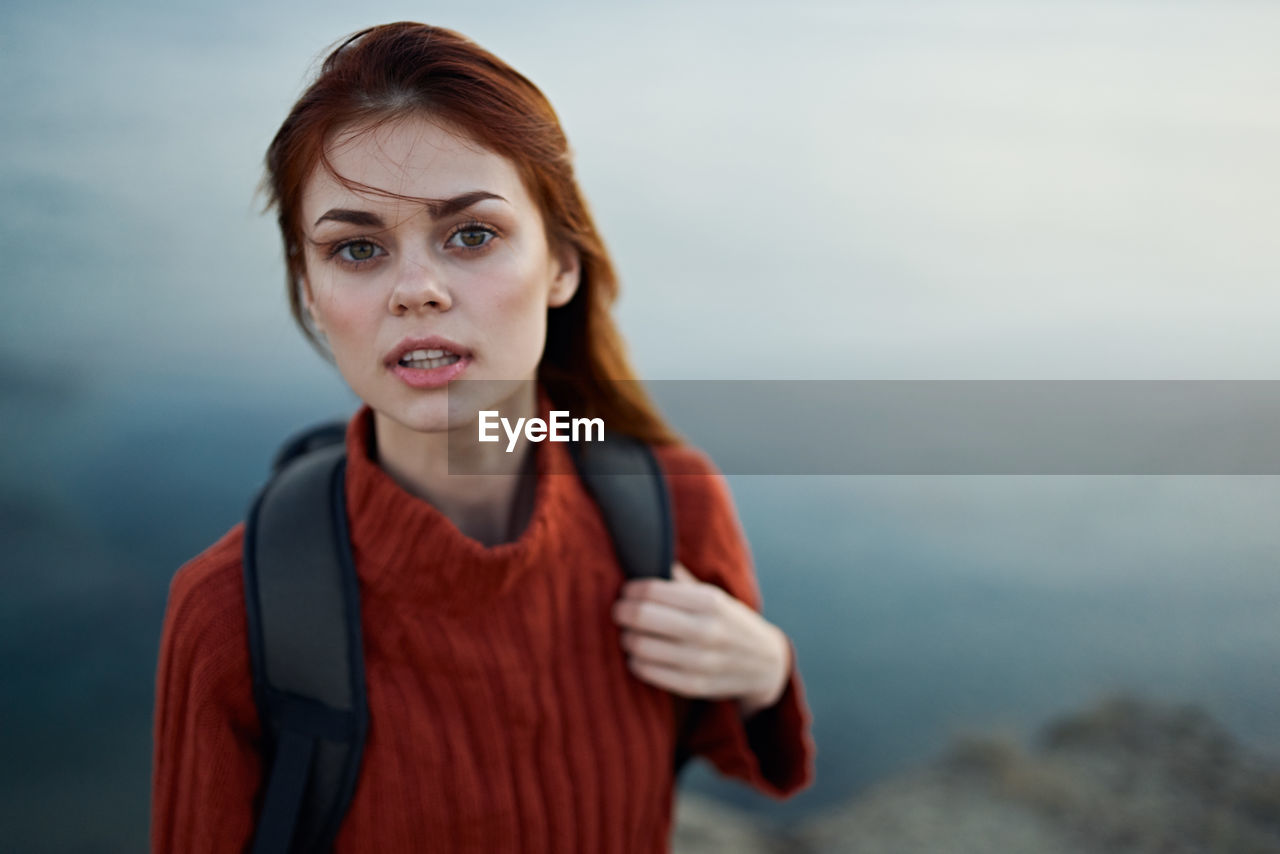 Portrait of young woman standing against sea