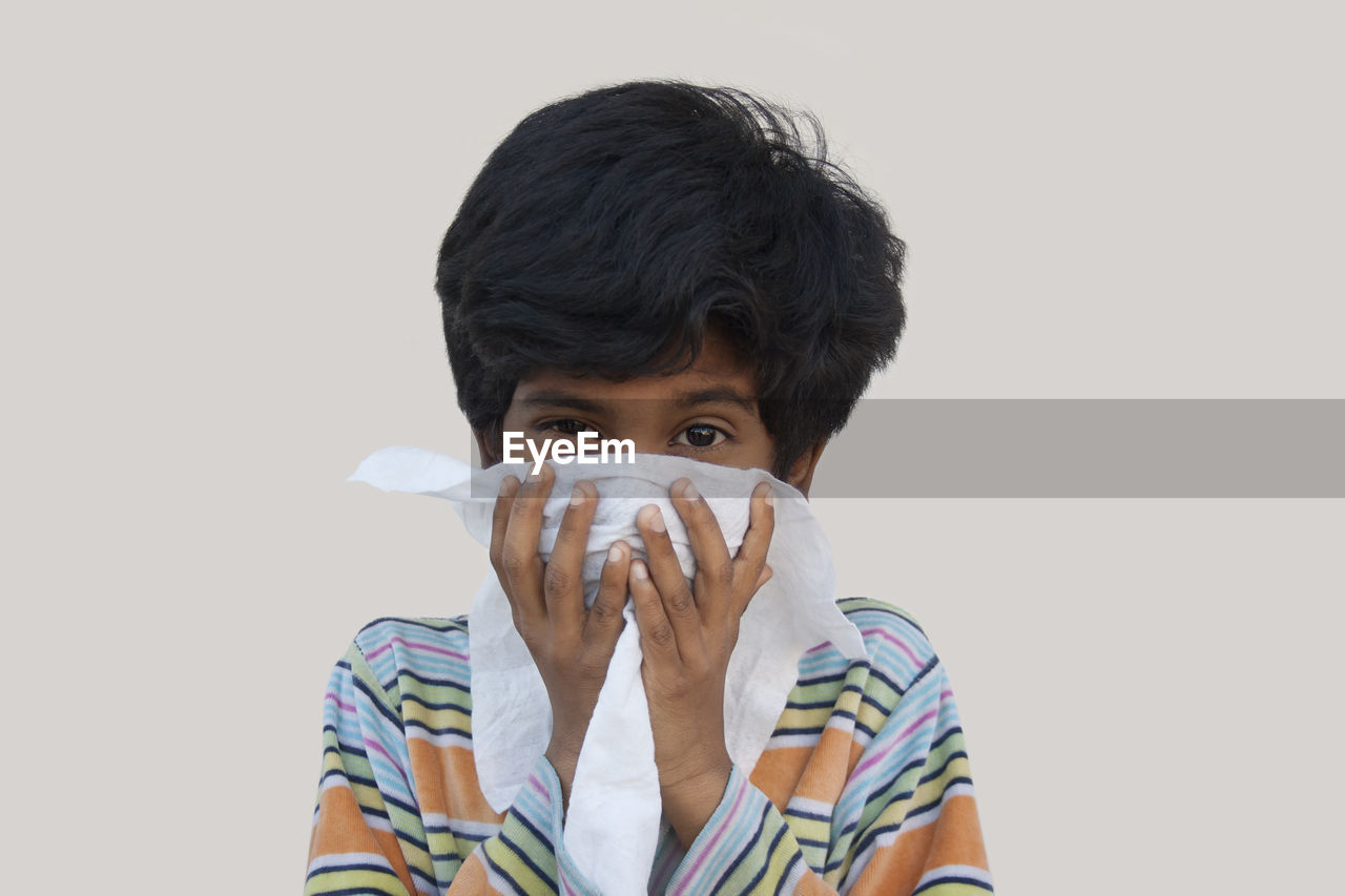 PORTRAIT OF BOY HOLDING GRAY BACKGROUND