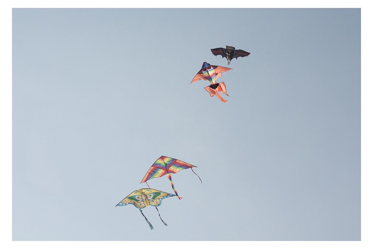 Low angle view of kites flying against clear sky