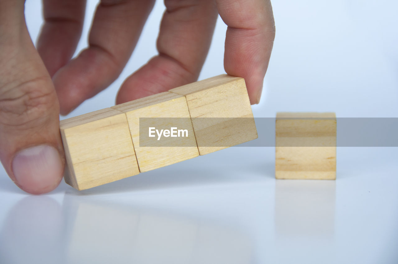 cropped hand of man holding wooden blocks on table