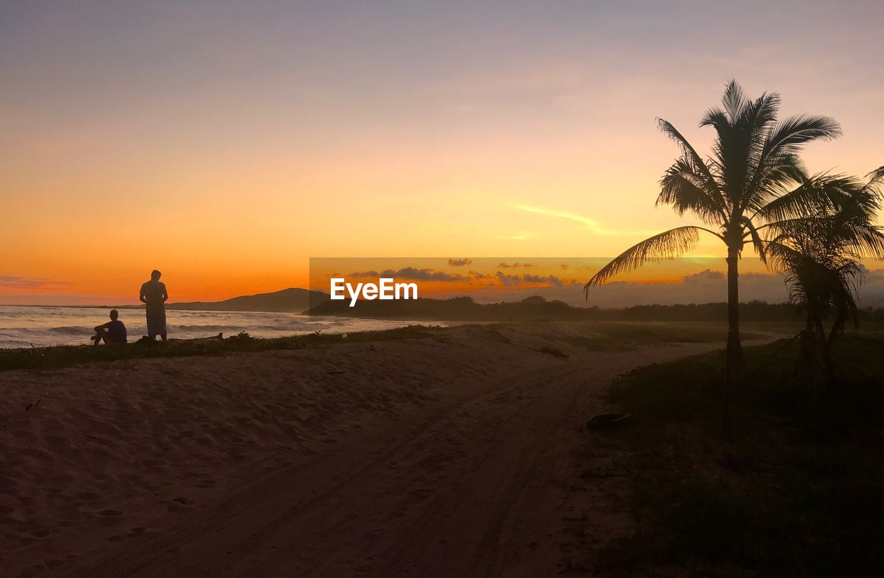 Friends standing at beach during sunset