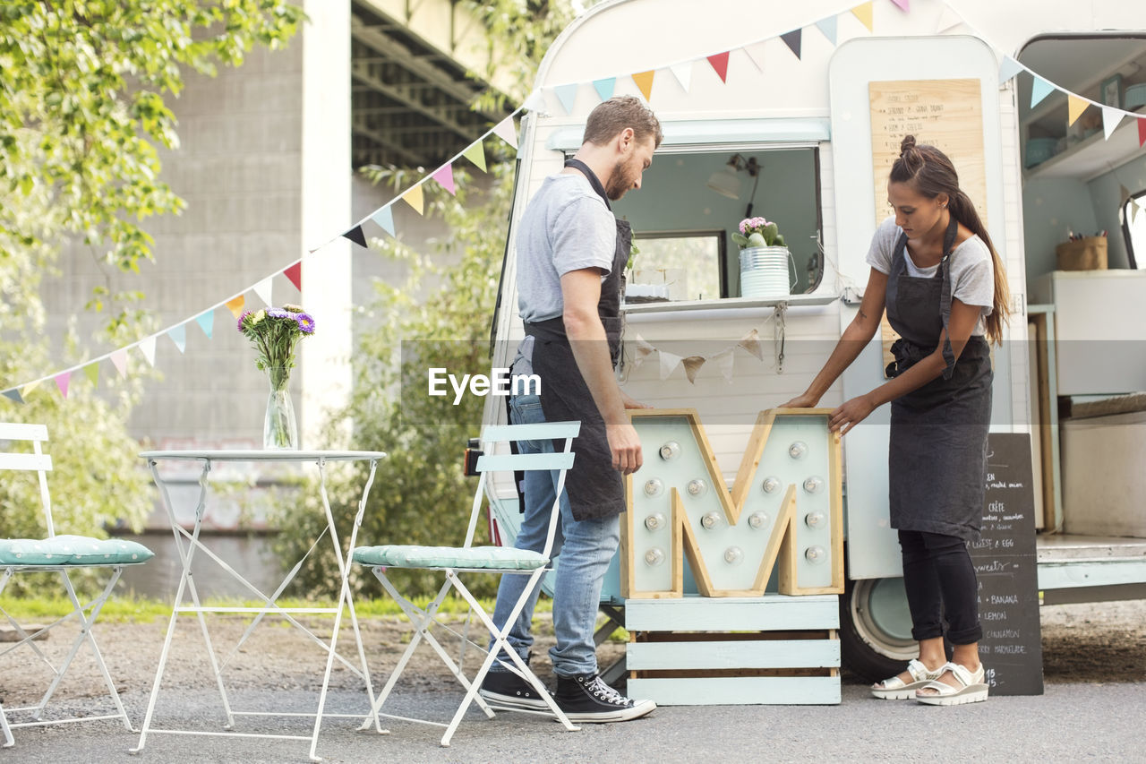 Owners placing letter m outside food truck on street