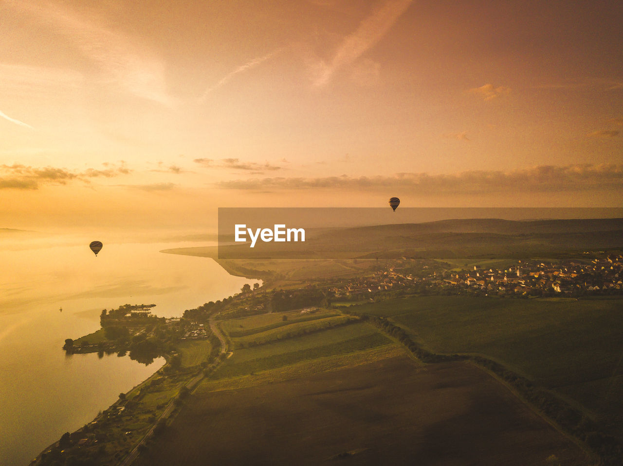 Hot air balloon flying over landscape against sky during sunset