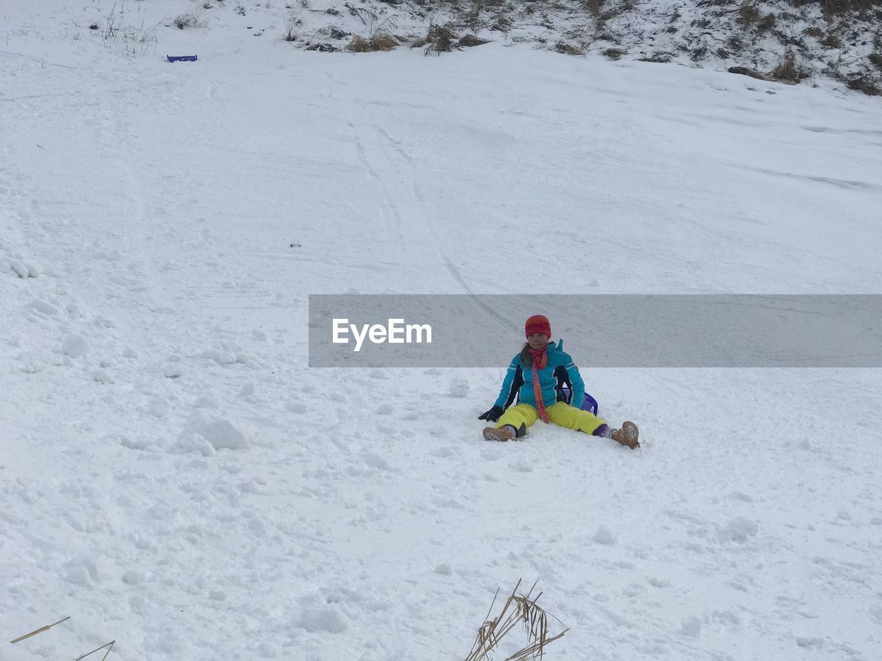 Low angle view of girl sitting on ski slope