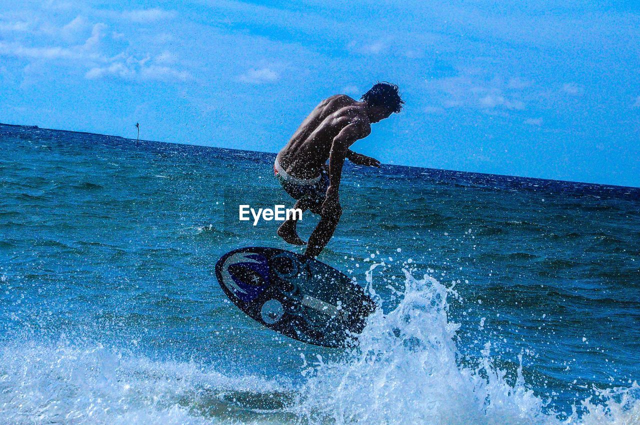 MAN SURFING IN SEA AGAINST SKY