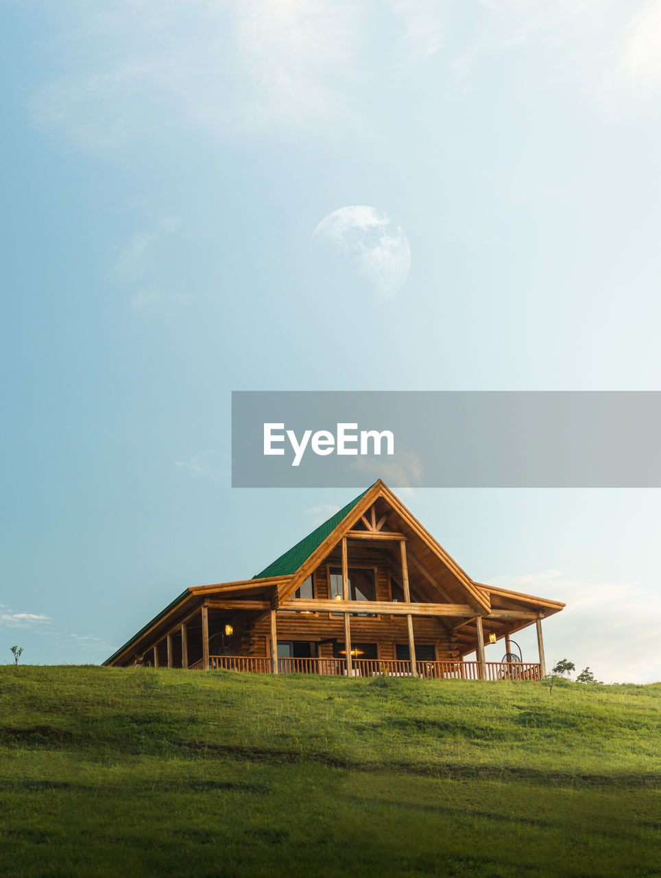 Scenic and peaceful isolated wooden modern cabin house landscape with blue sky and a moon