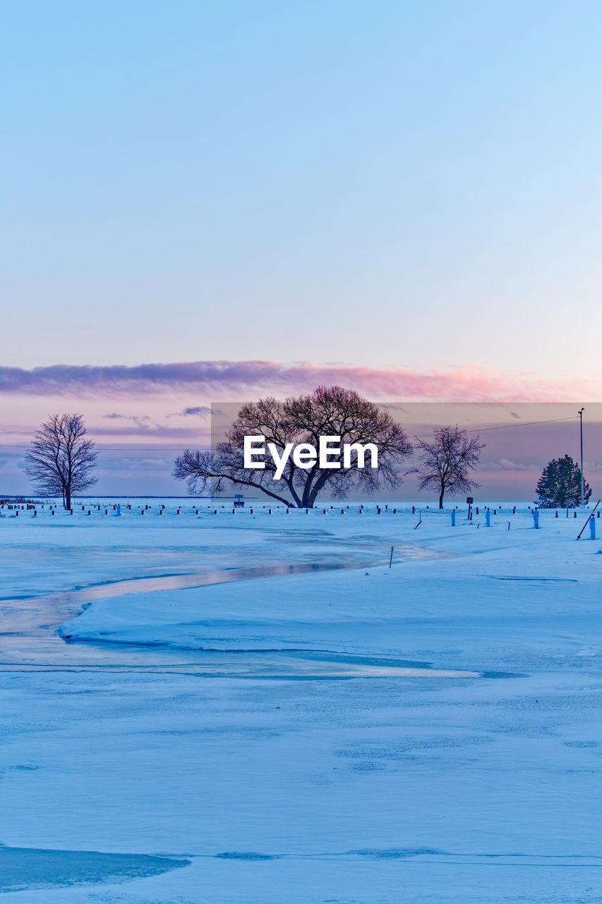 Scenic view of snow field against clear sky during sunset