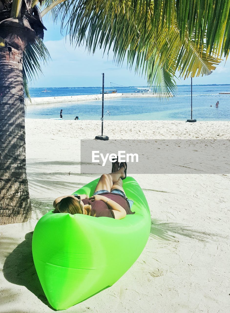 YOUNG WOMAN LYING ON BEACH