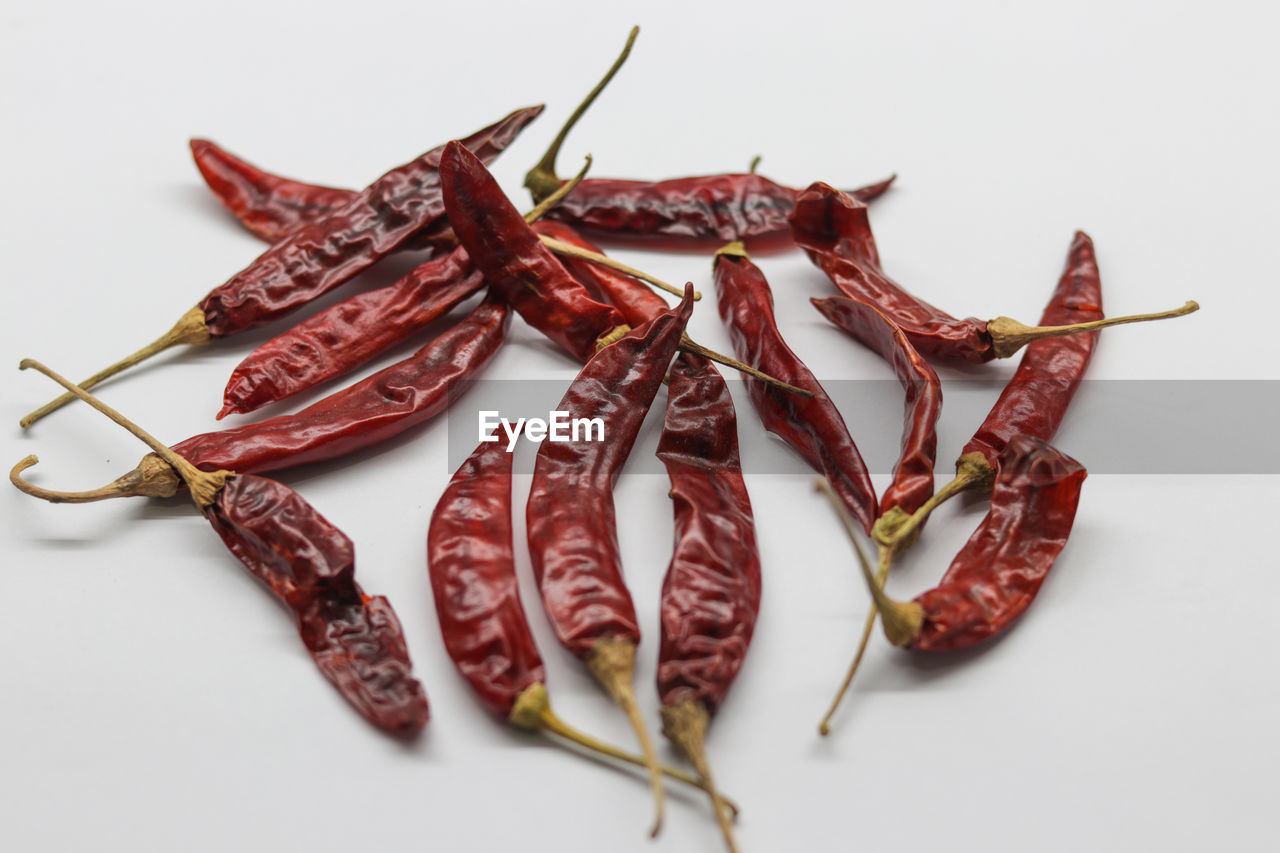 HIGH ANGLE VIEW OF RED CHILI PEPPERS AGAINST WHITE BACKGROUND
