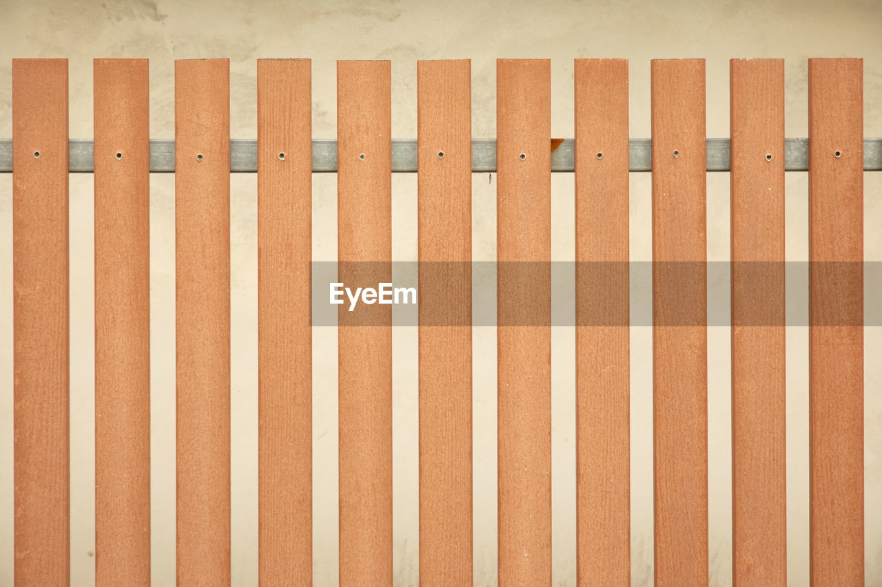 CLOSE-UP OF WHITE FENCE ON WOODEN WALL