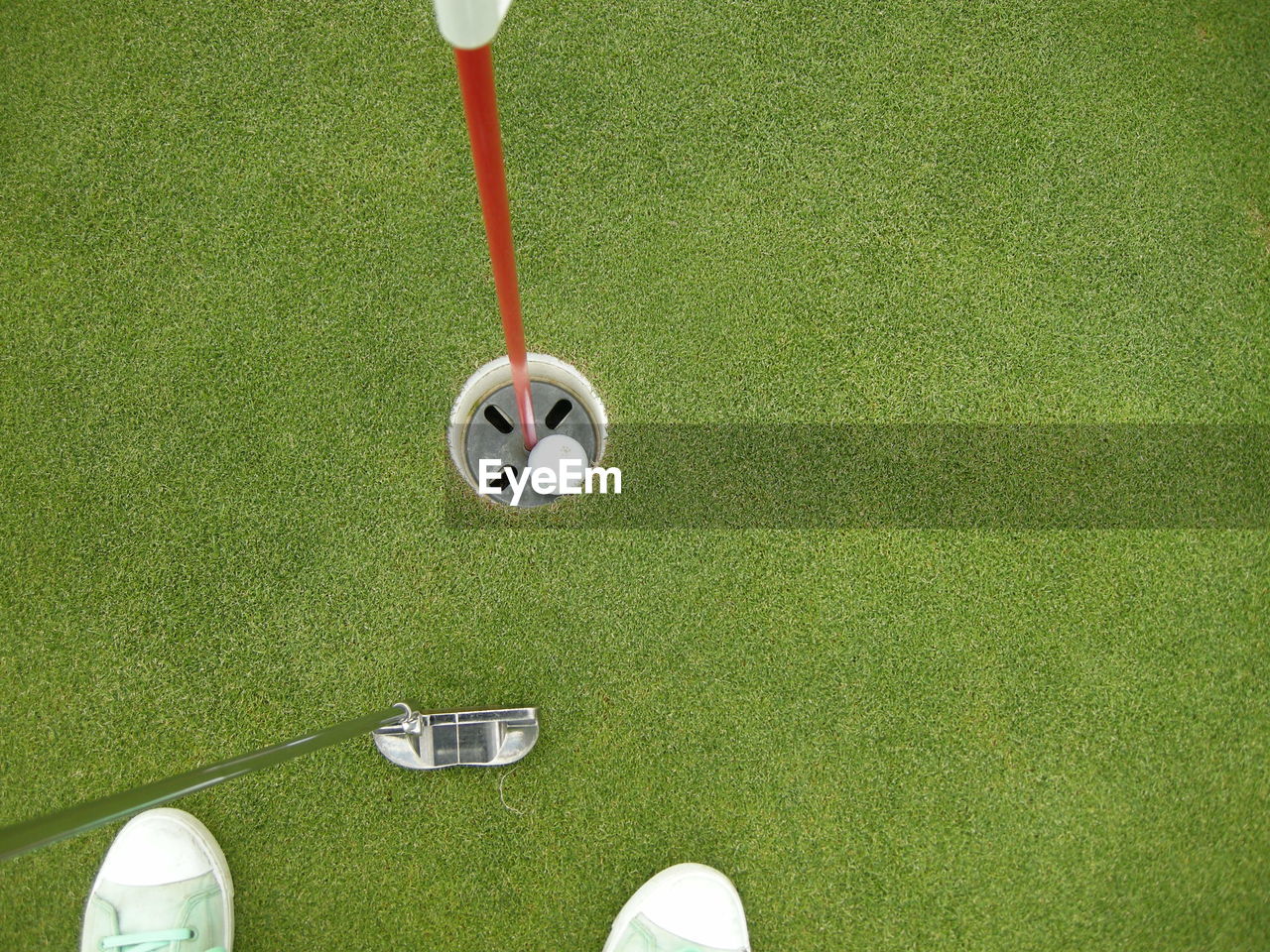 High angle view of canvas shoes and golf club by hole at course