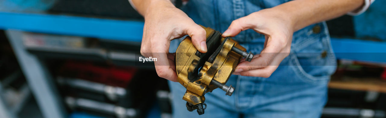 Mechanic woman checking caliper brake system on garage