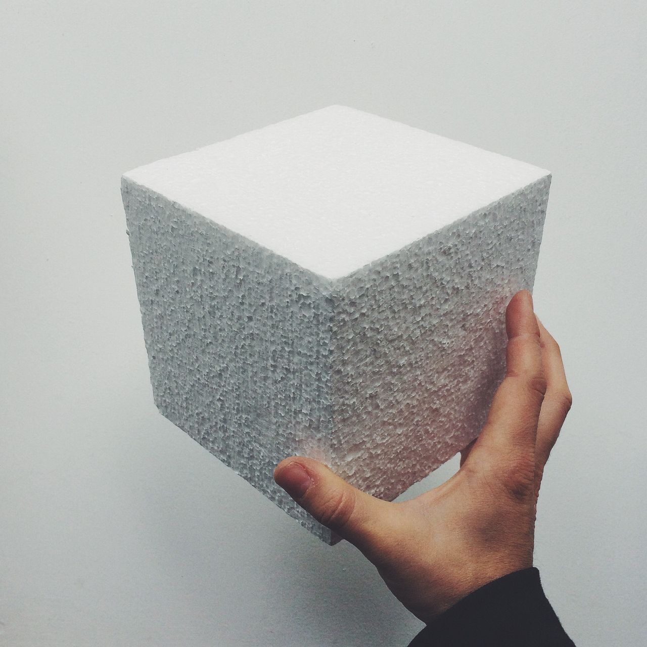 Man holding concrete cube against wall