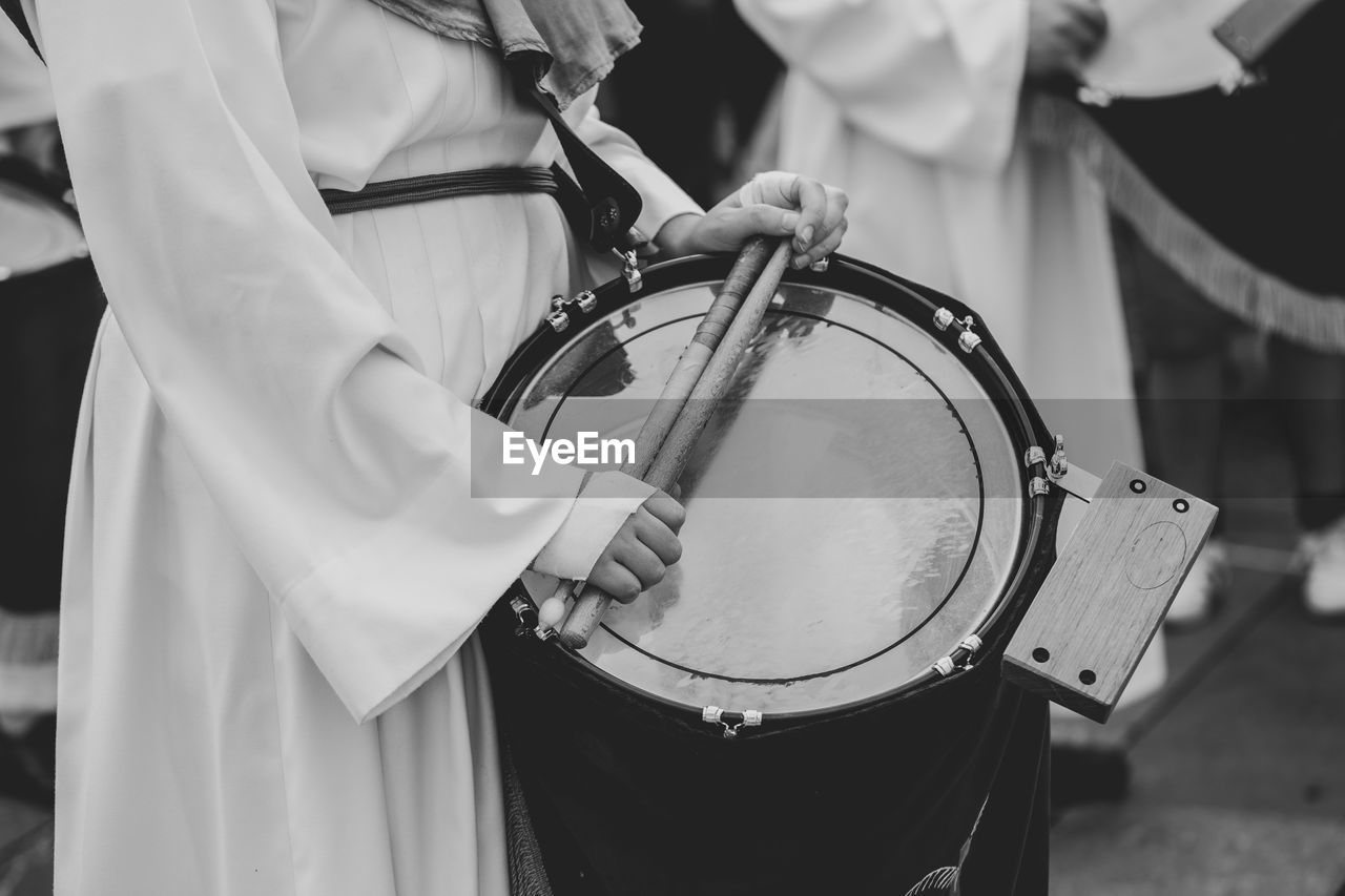 Midsection of person playing drum at parade