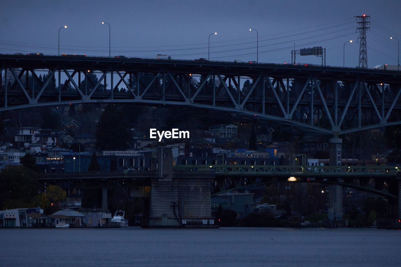 Bridge over river against sky at blue hour