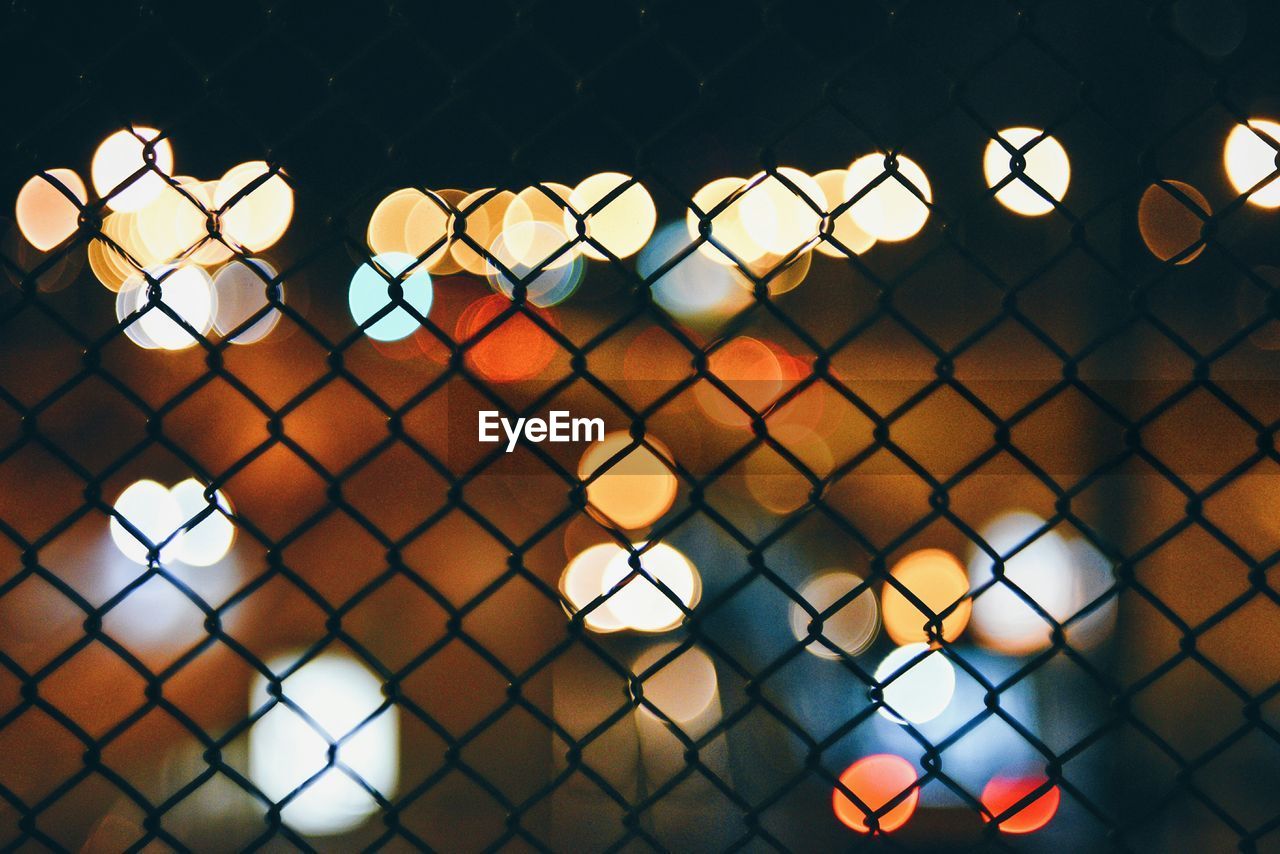 Colorful illuminated lights seen from chain link fence at night