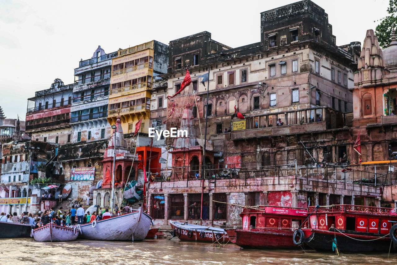 Boats moored in canal by buildings against sky in city