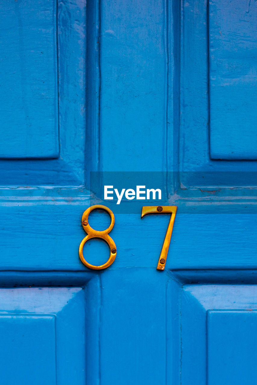 House number 87 on a blue wooden front door in london 