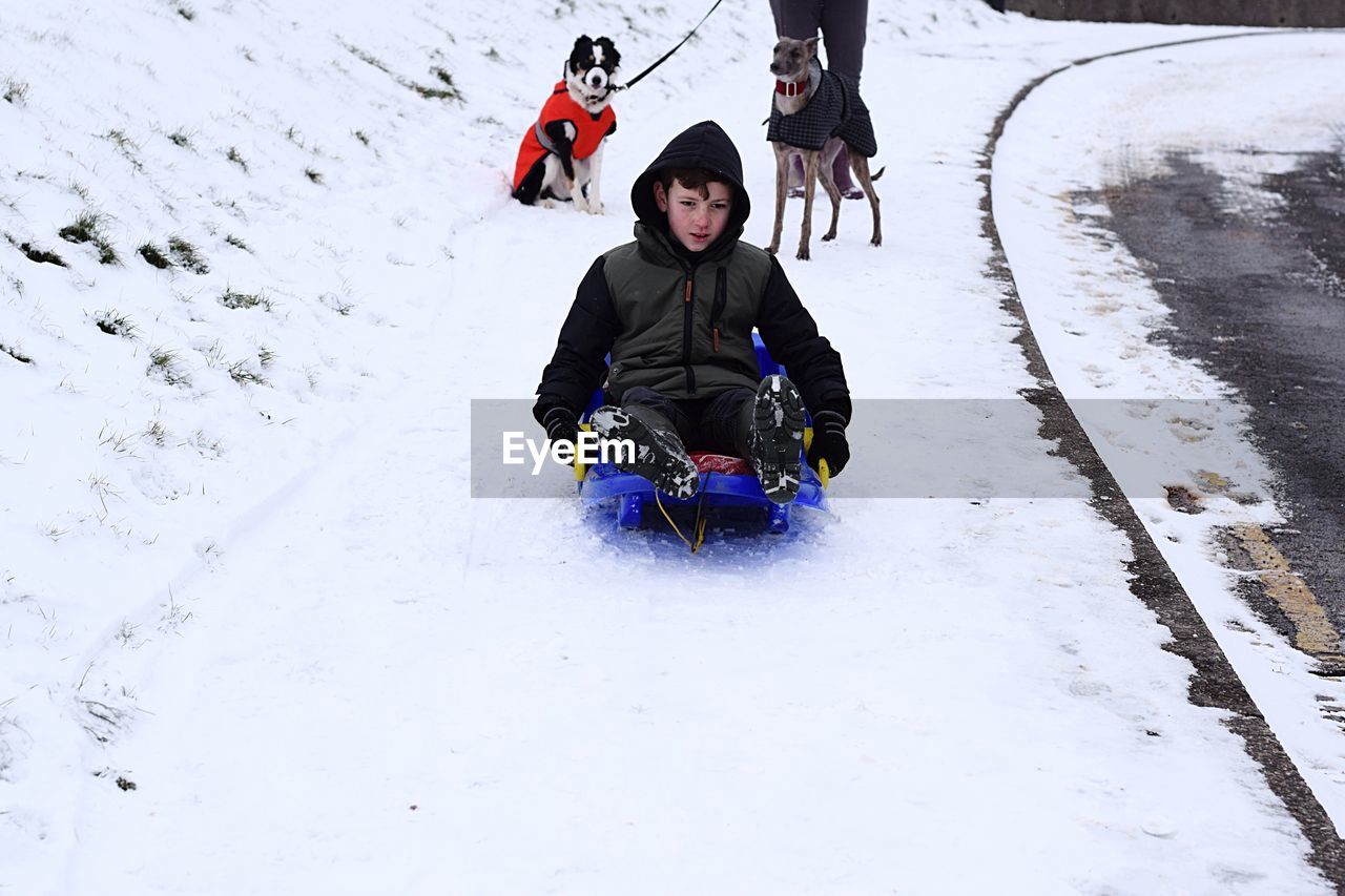 Boy tobogganing on snow covered field