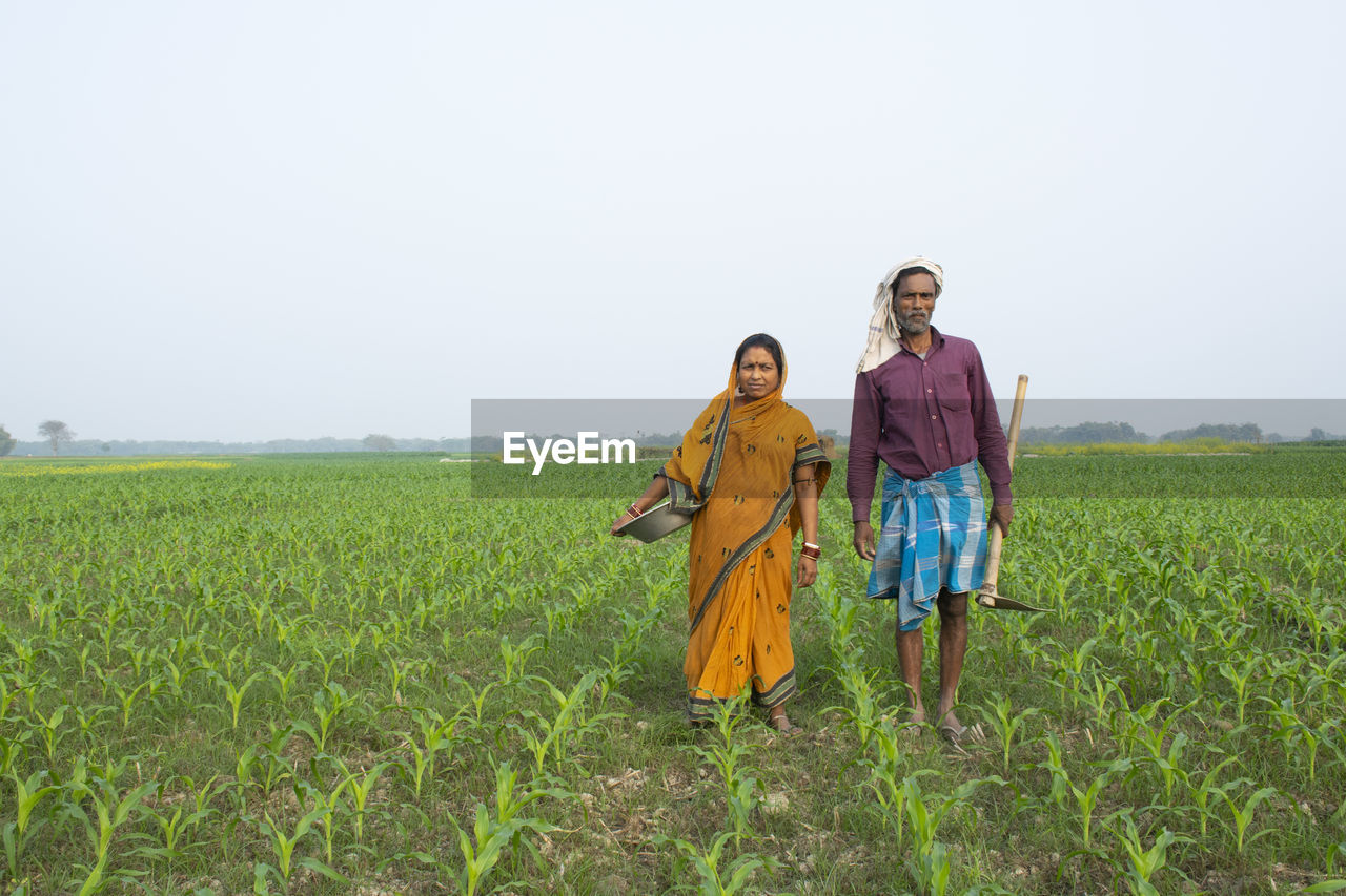 REAR VIEW OF TWO WOMEN STANDING ON FIELD