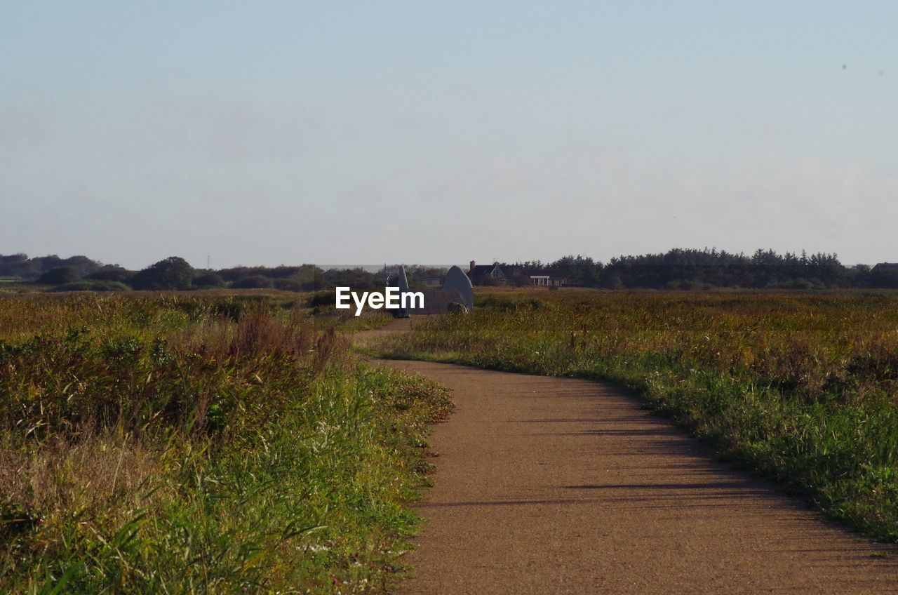 DIRT ROAD AMIDST AGRICULTURAL FIELD AGAINST SKY