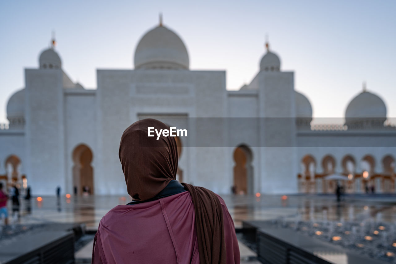 REAR VIEW OF PEOPLE OUTSIDE TEMPLE AGAINST BUILDINGS