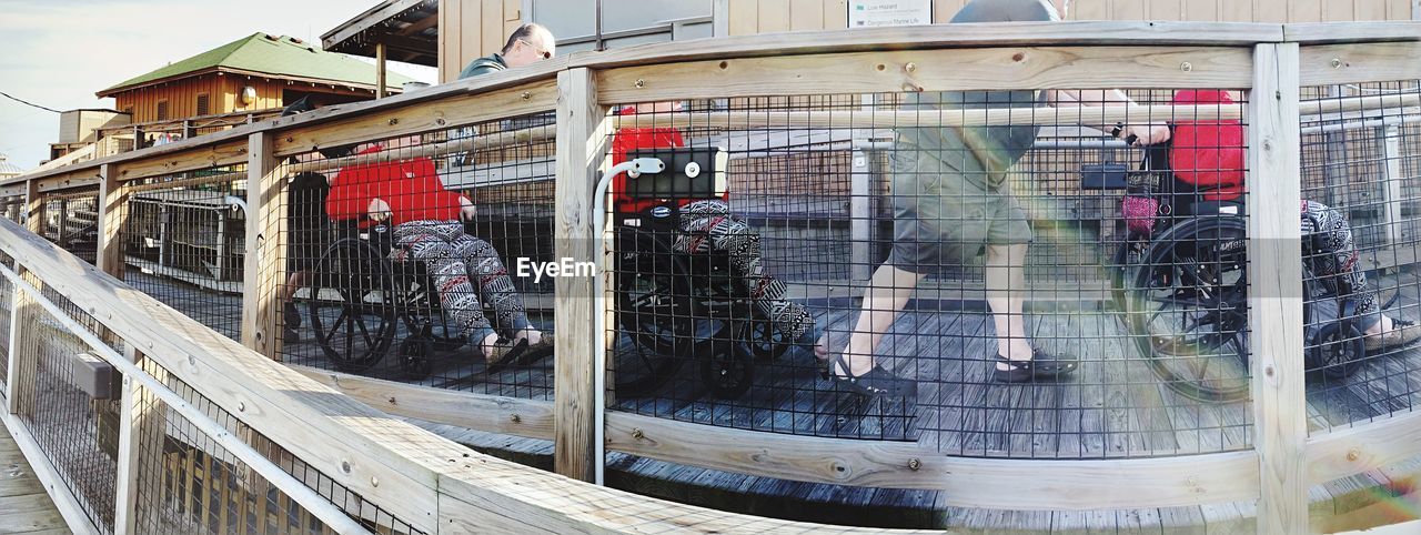 Digital composite image of man pushing wheelchair seen through railing